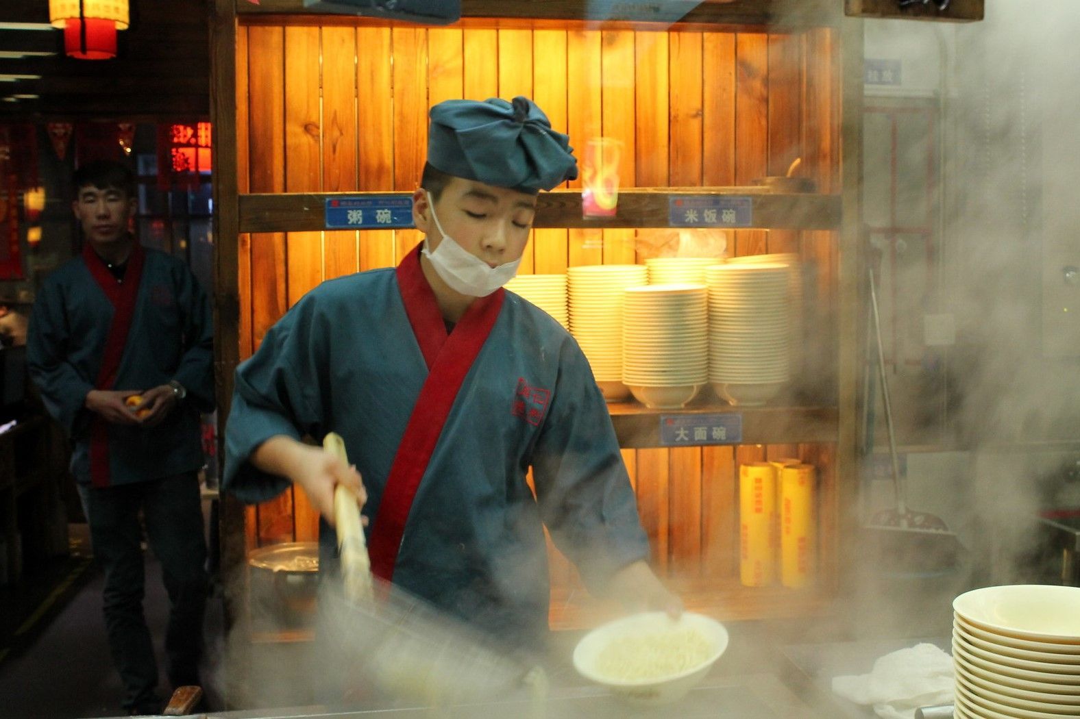 A cook working over a steaming pot